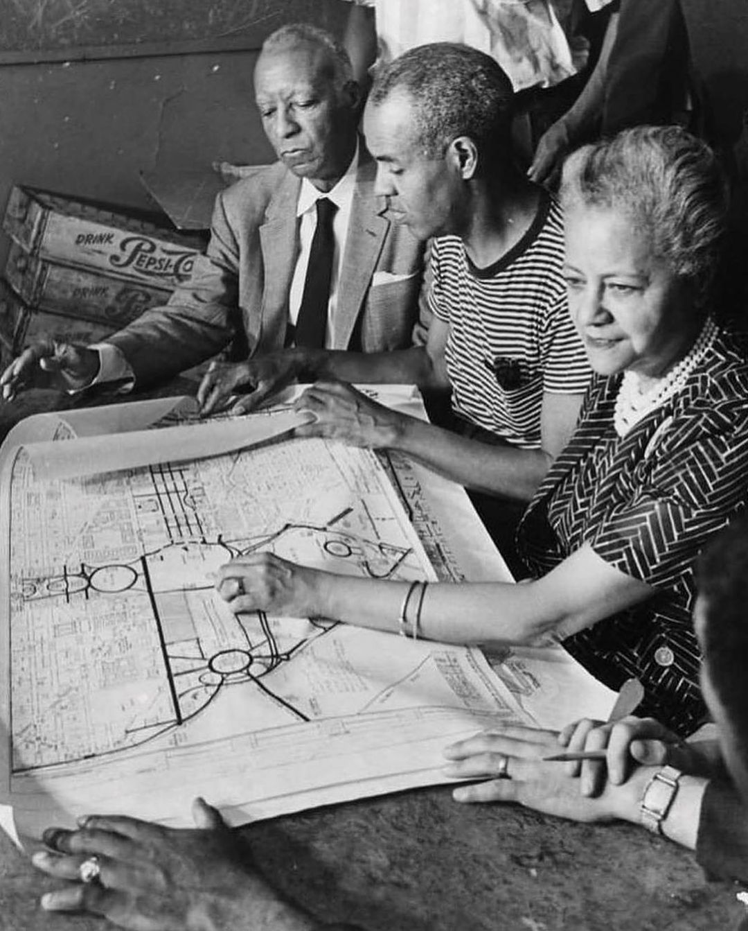 A. Philip Randolph, Roy Wilkins and Anna Arnold Hedgeman sit at a table with a map spread out showing the planned route for the March on Washington. 