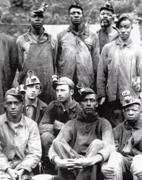 A group of both Black and white miners wearing early headlamps.