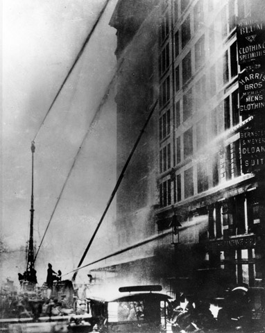 Black white photo of firefighters spraying water at the Triangle building.