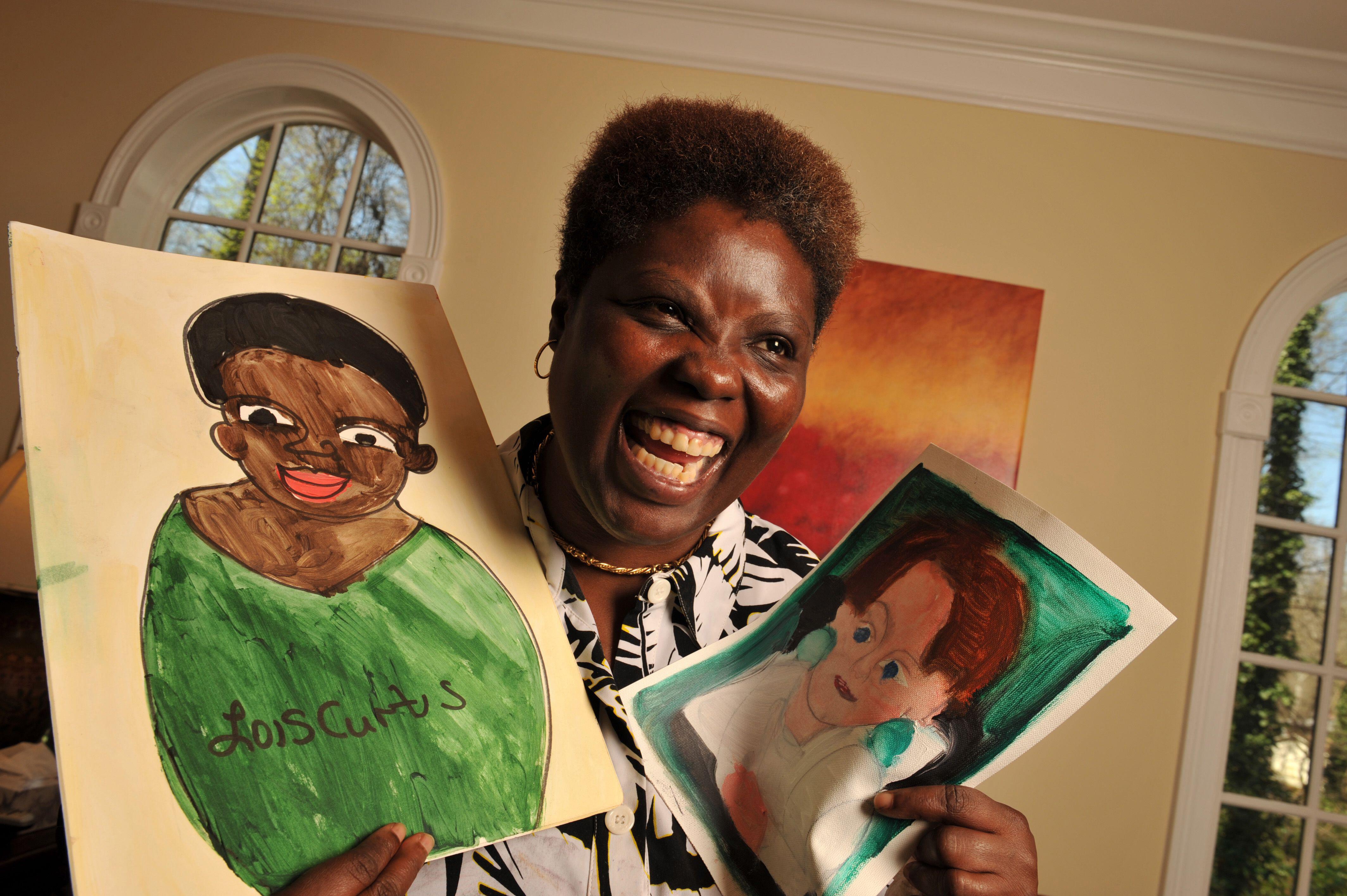 A picture of Lois Curtis smiling with two drawings in her hand