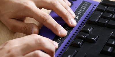 Close-up photo of hands typing on a braille keyboard.