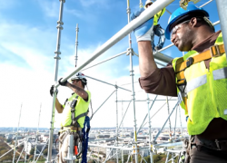 Two men working at heights wear fall protection gear