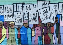 Colorful mural recreating a 1968 black and white photograph of Black workers in Memphis holding signs that read "I am a man"