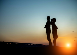 Silhouettes of two young people against the setting sun