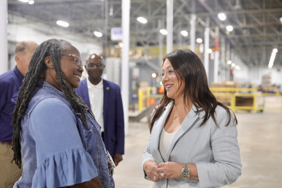 Secretary Lori Chavez-DeRemer speaking with a female worker in a warehouse-type workplace.