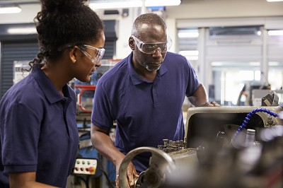 A young woman apprentice works in a machine shop with her mentor