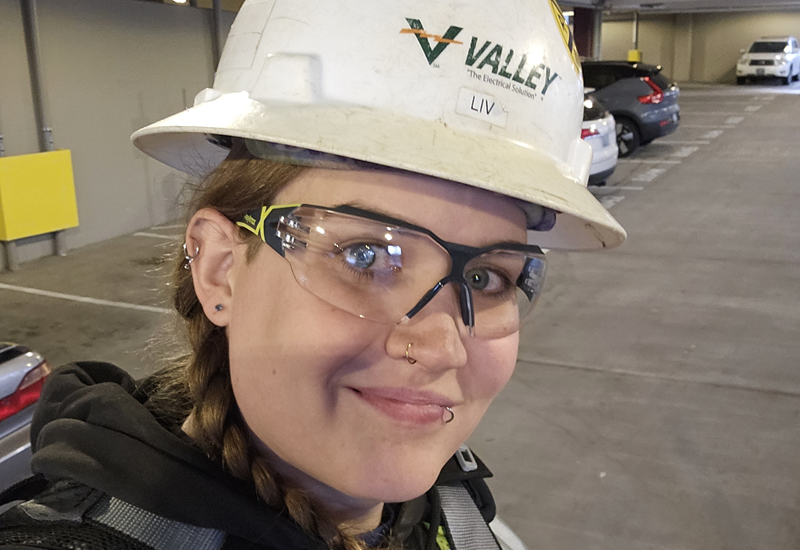 Close-up photo of Olivia Yelton, an electrical worker, wearing a hard hat and safety goggles.
