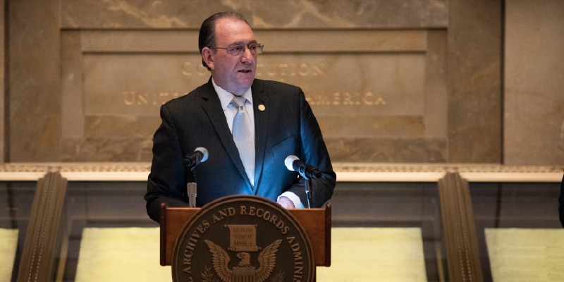 Former ODEP Assistant Secretary Neil Romano stands in front of a podium at a ceremony where he was sworn in as the Chairman of the National Council on Disability.