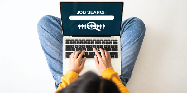 A woman types on a laptop open to a page reading 'job search'.