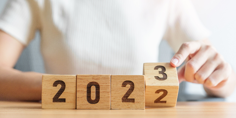 A woman turns over the number block in a row of four blocks to change the year shown from 2022 to 2023