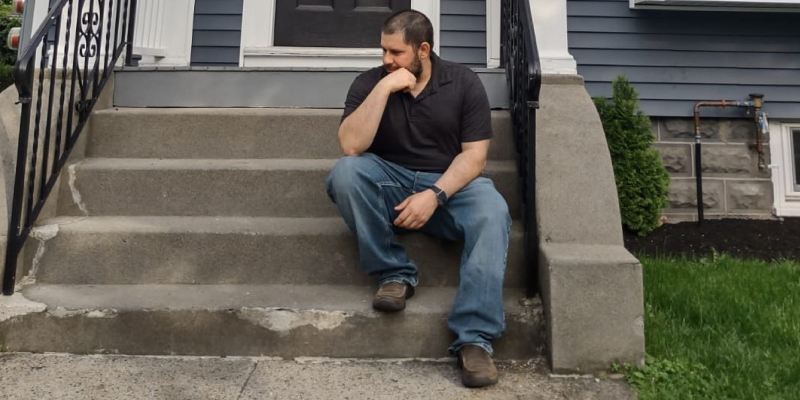 Diego Jimenez sitting on the front steps of a house.