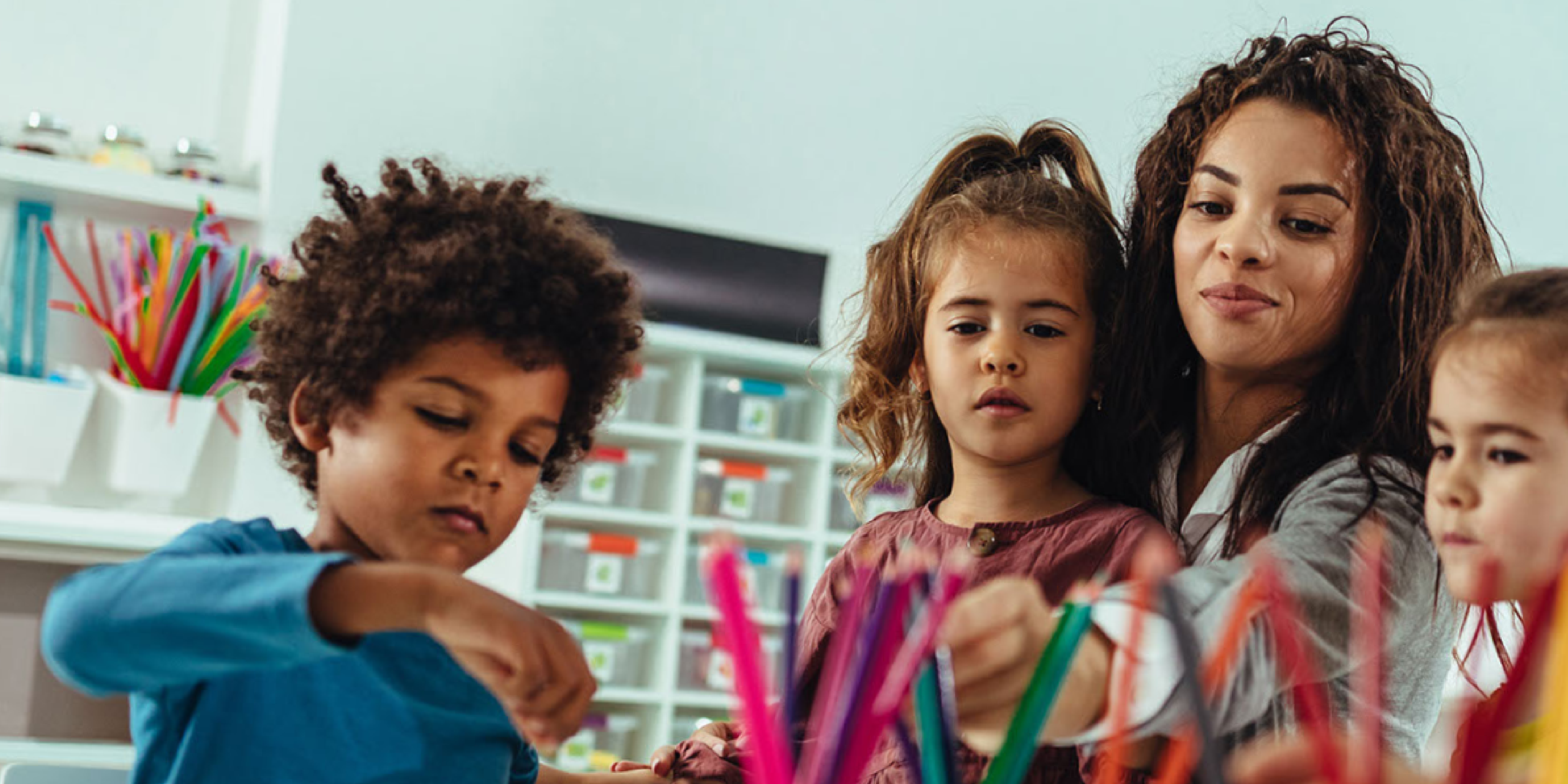 A mother and two children sitting and coloring. 