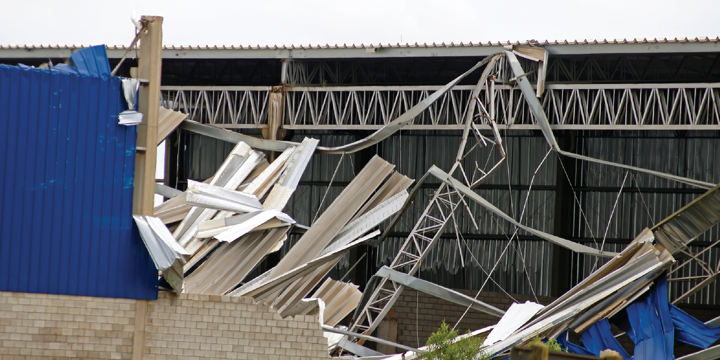 Visible wind damage following a storm - a roof and siding have been ripped from a building.