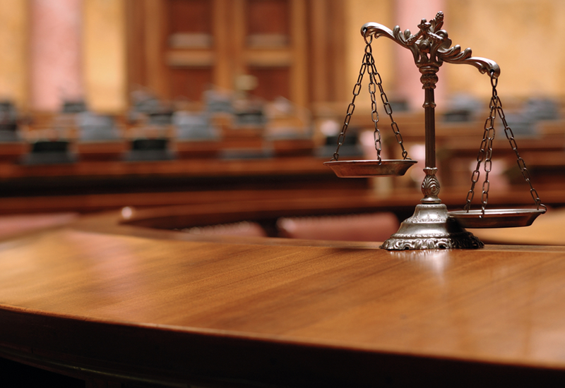 Hình ảnh cán cân công lý trên bàn trong một căn phòng xử án.