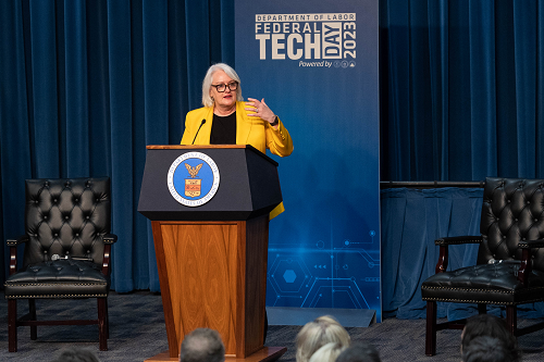 Chief Information Officers Clare Martorana from the Office of Management and Budget speaks at a podium with the Labor Department seal. A banner behind her says Department of Labor Federal Tech Day 2023.