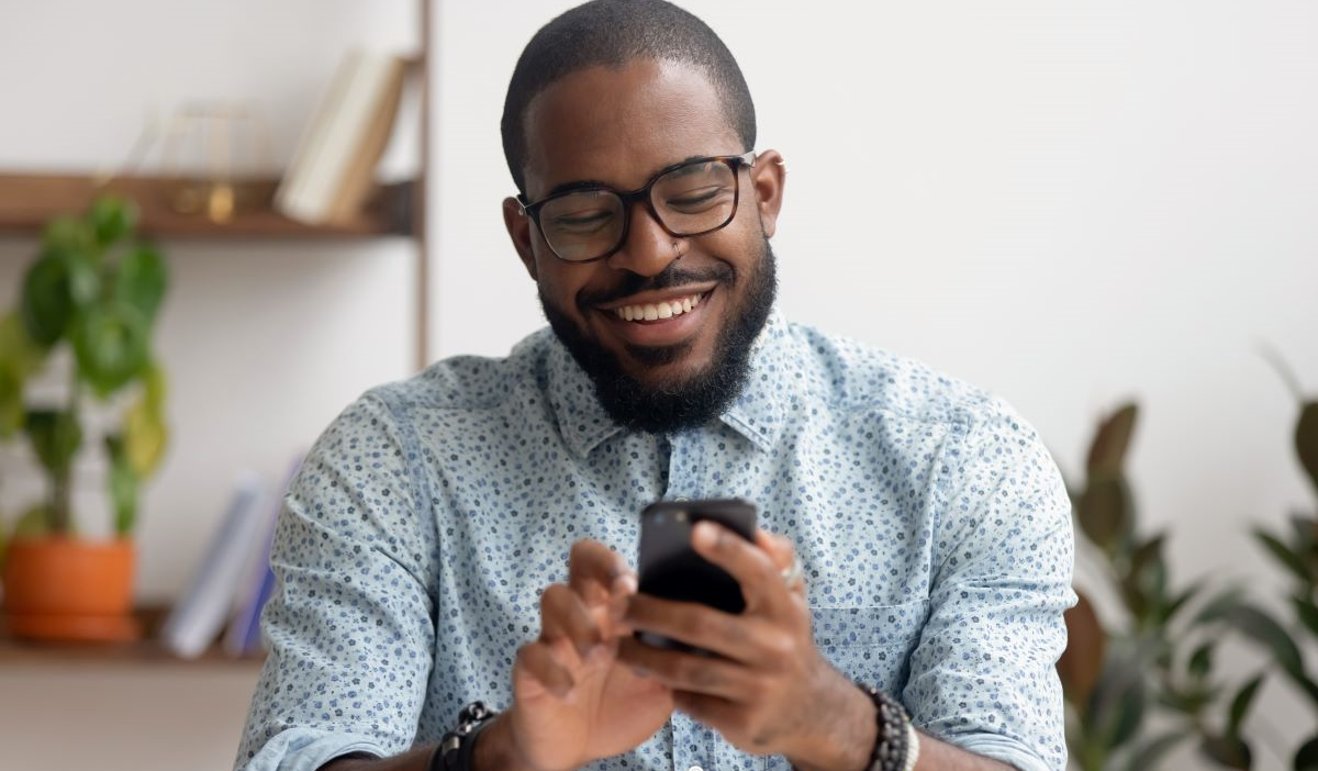 A man smiles while using a smartphone