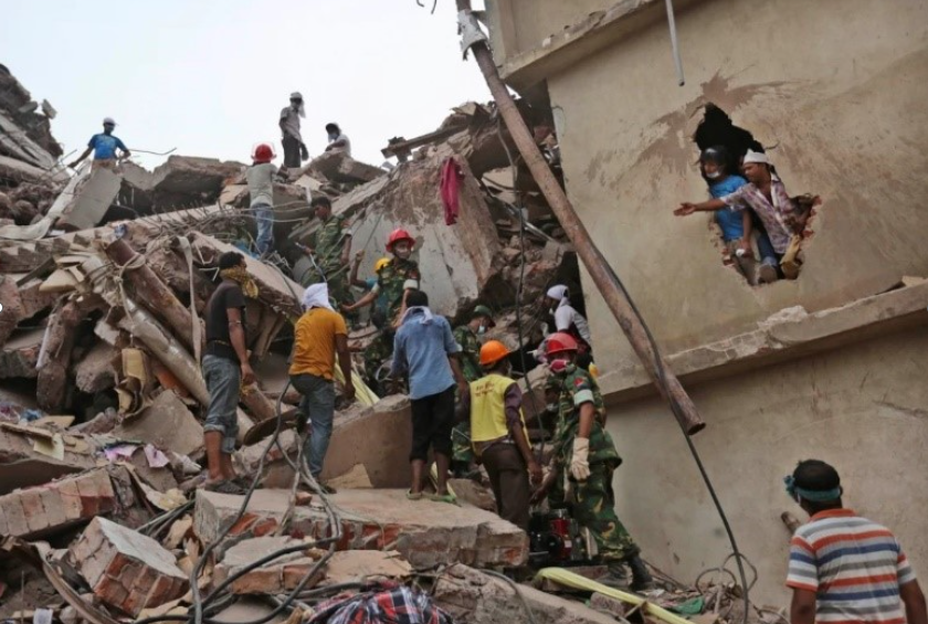 People mill around the wreckage of a collapsed building.