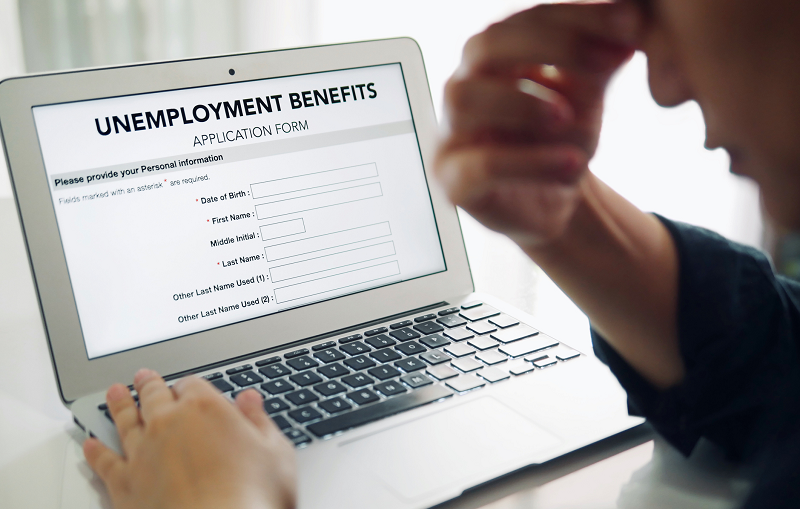 A man who looks discouraged fills out an online application for unemployment benefits