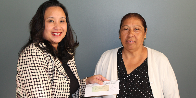 Bertha Gonzalez (right) receives a check for back wages from Kimchi Bui, district director for the Wage and Hour Division in Los Angeles.