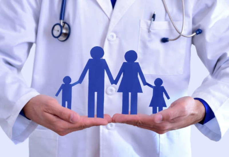 Blue, paper cut out of family in the hands of a medical professional.