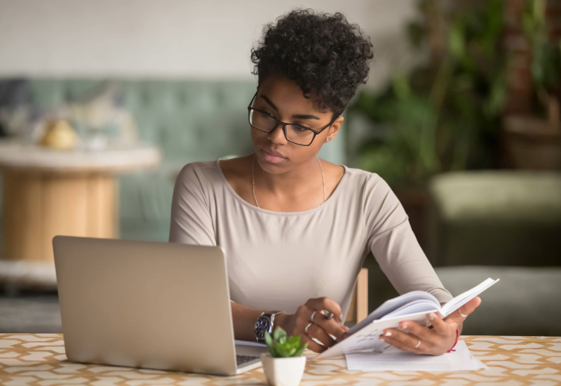 A young woman looks at her computer while evaluating her finances.