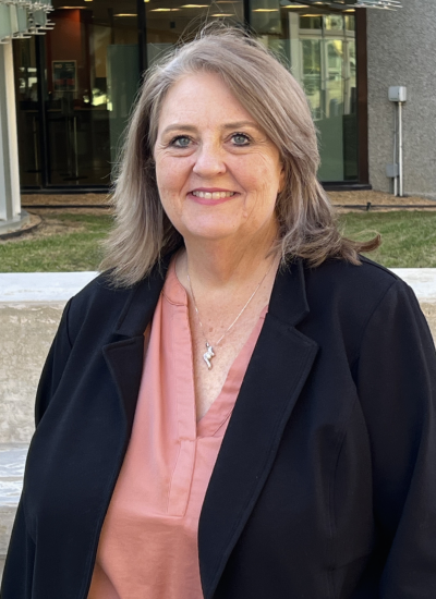 Dorinda Hughes, wearing a dark blue blazer, stands outside the Birmingham office.