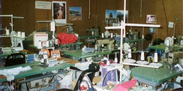 Photo of the sweatshop, with sewing machines and piles of fabric, where workers toiled in forced labor