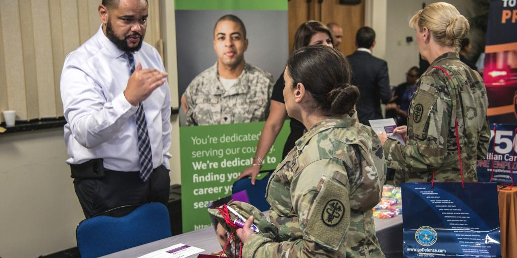 Photo from a hiring fair of a civilian employer speaking with a service member