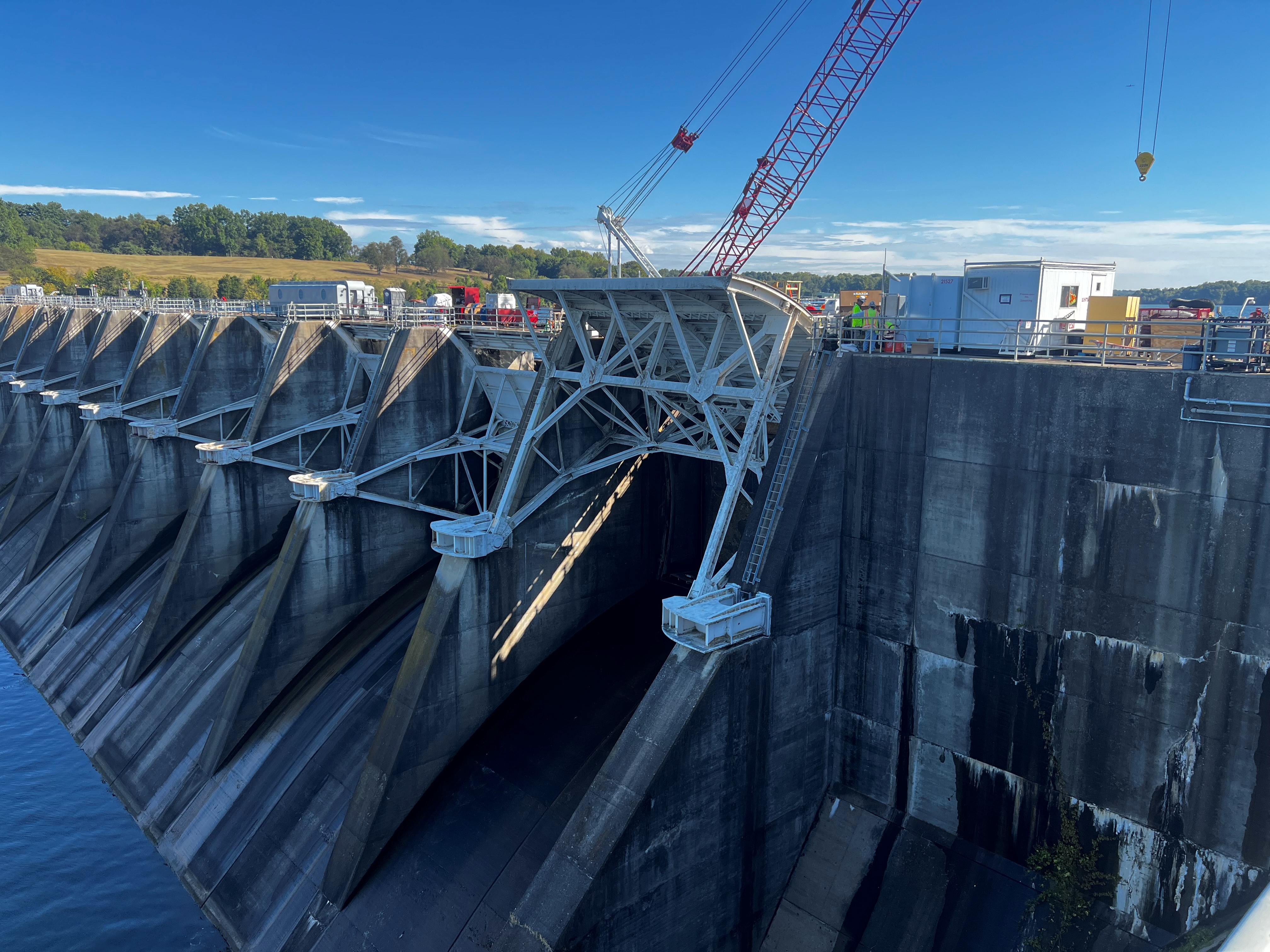 A view of a large dam with construction equipment on top, including a crane.