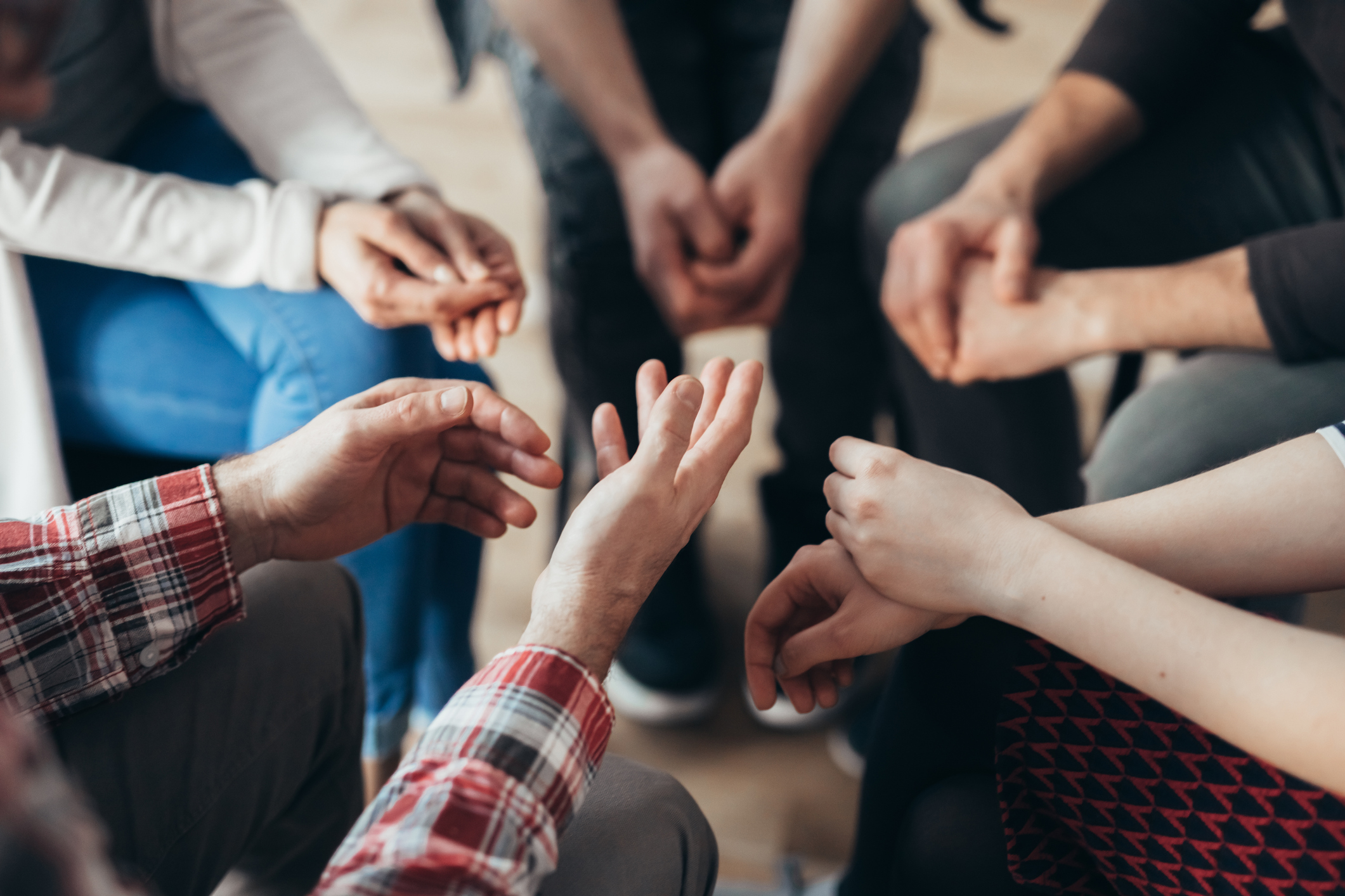 Picture shows the hands of a group of young adults sitting in a circle.