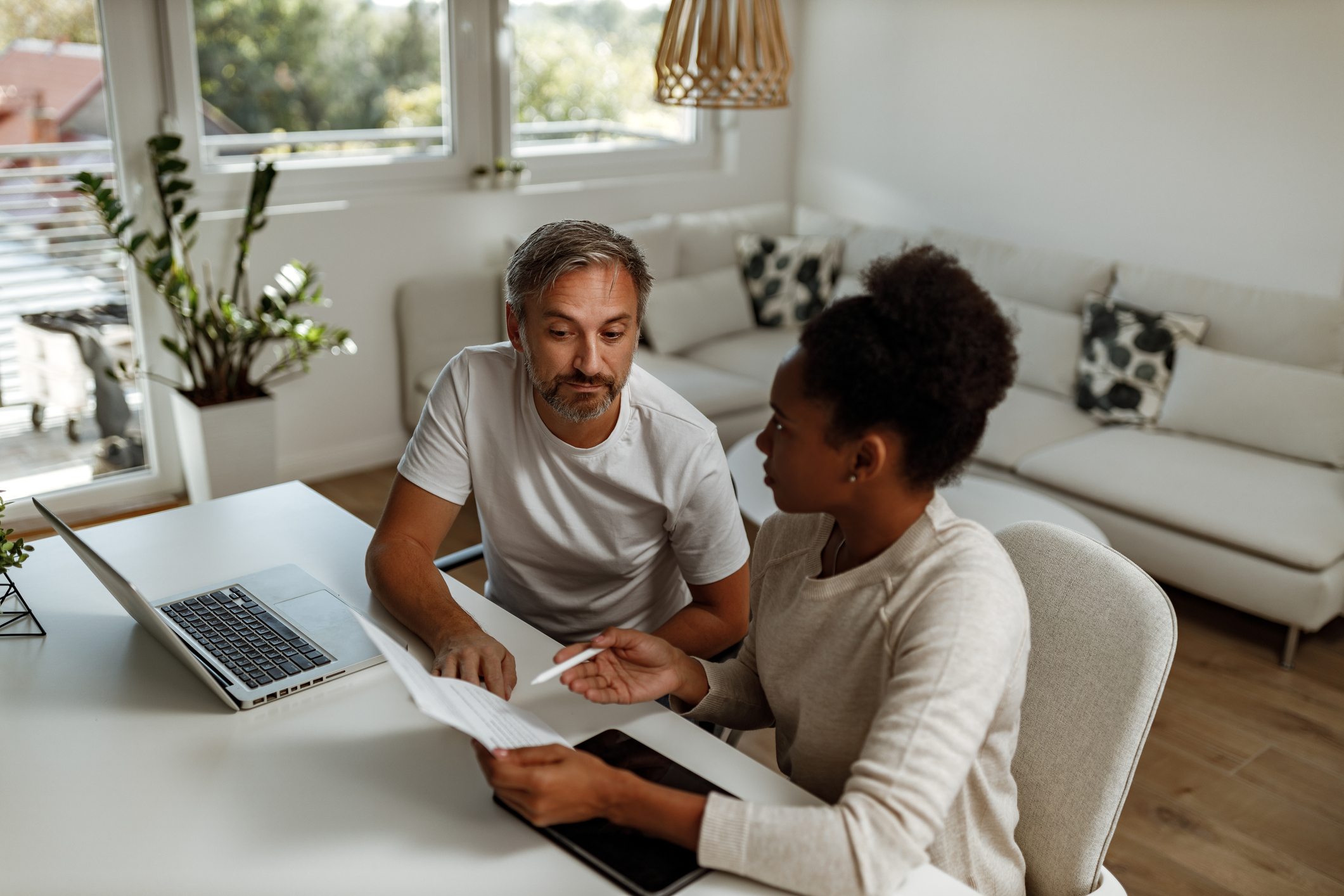 Two people sit at a table with a laptop and financial documents