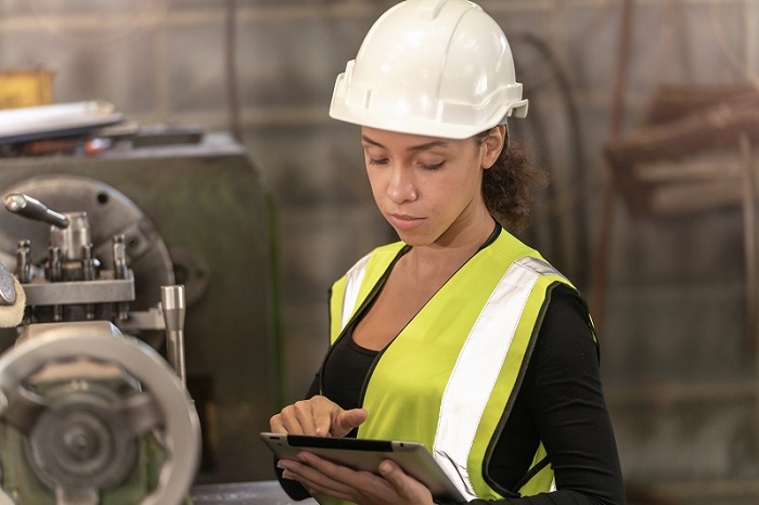 Woman wearing a hardhat and orange vest. 