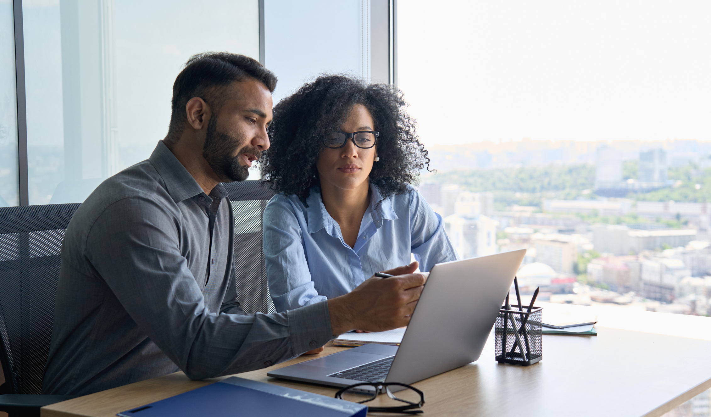 two workers sit at a laptop