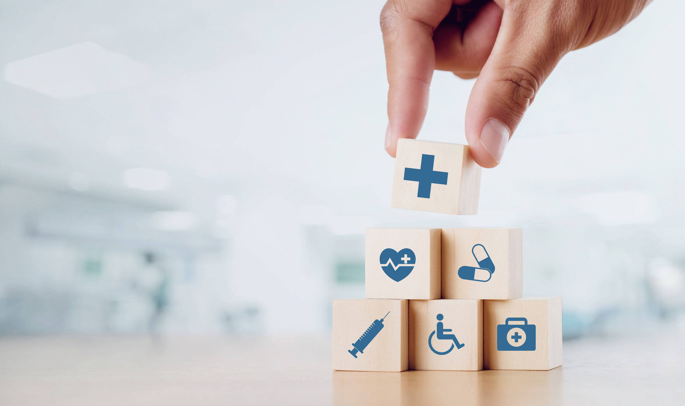 Close up man hand arranging wood block with healthcare medical icon on hospital background. 