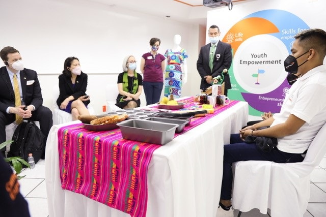 Julie Su sitting with others watching the presentation of a grant participant on youth empowerment.