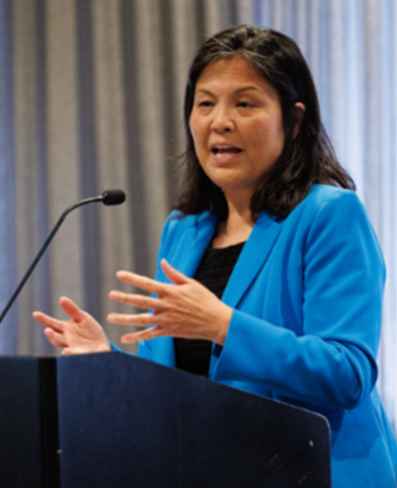 Acting Secretary Su, wearing a blue jacket, speaks at a podium. 