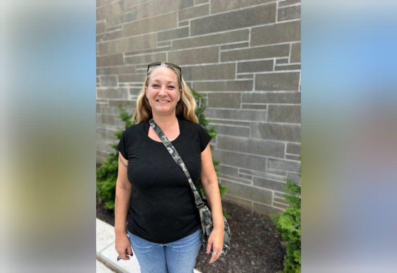 A woman posing in front of a brick wall.