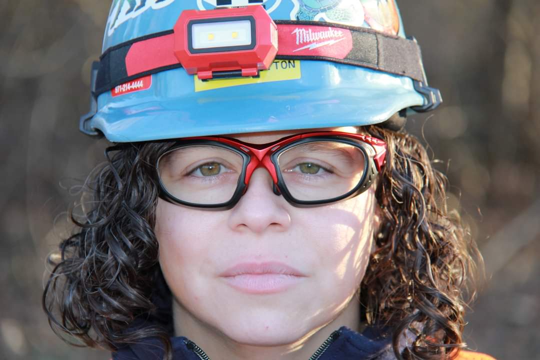 Headshot of Leslie Cotton in a blue hard hat and safety goggles.