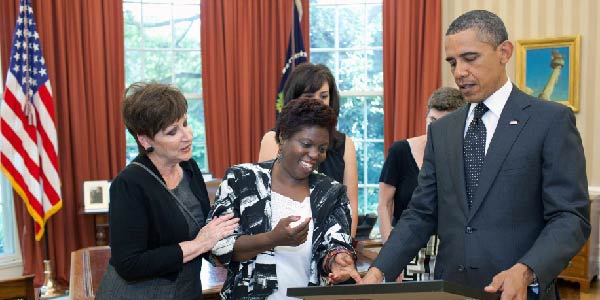 Lois Curtis stands next to Barack Obama in the Oval Office. The president is holding a painting.