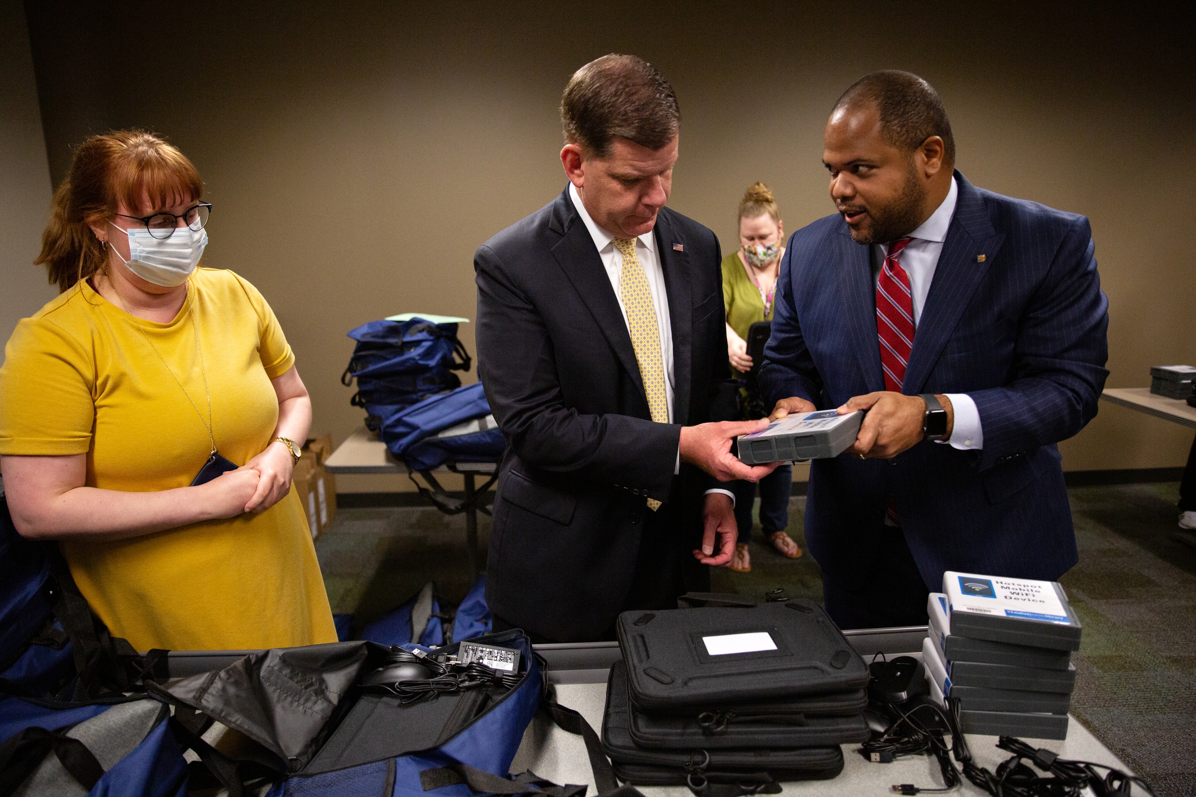 Dallas Mayor Eric Johnson passes a Mi-Fi, or portable Wi-Fi device, to U.S. Secretary of Labor Marty Walsh to place in a package at the J. Erik Jonsson Central Library.