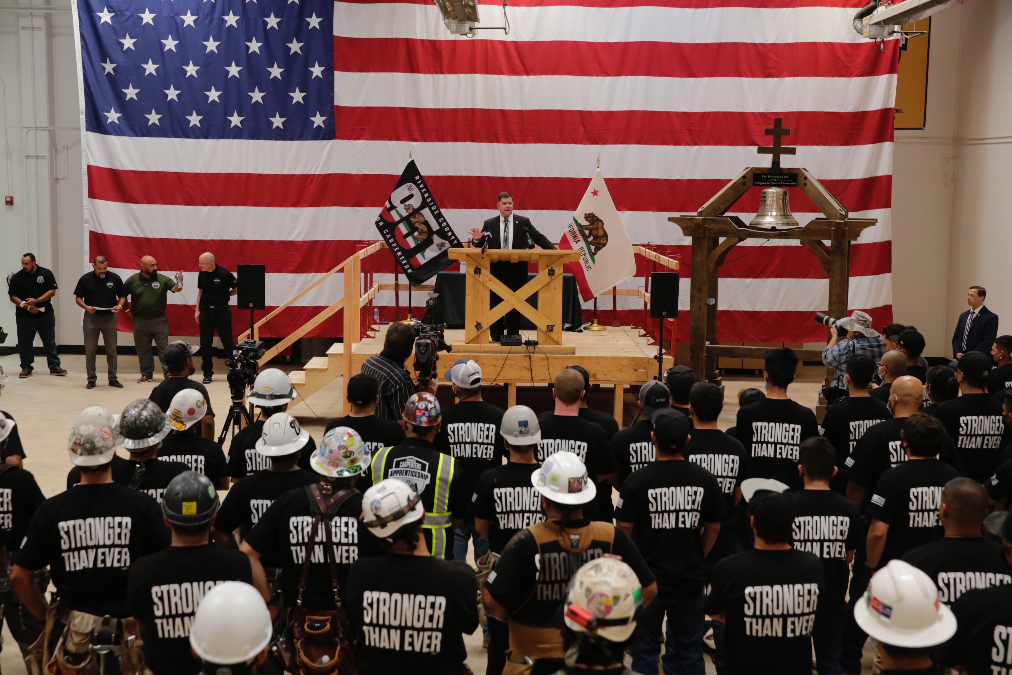 Secretary Marty Walsh stands in front of dozens of union workers wearing black shirts that read: stronger than ever.