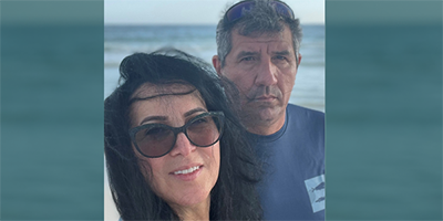 A man and a woman pose for a selfie in front of the ocean.