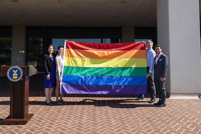 Deputy Secretary Julie Su standing with two individuals holding the PRIDE Flag. 
