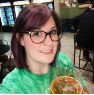 Photo of Samantha Powers wearing a green shirt with a beer in hand. 