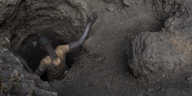 A person enters a dark and narrow mine shaft.