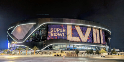 Exterior shot of a football stadium in Las Vegas with an enormous sign on it reading "Super Bowl LVIII"