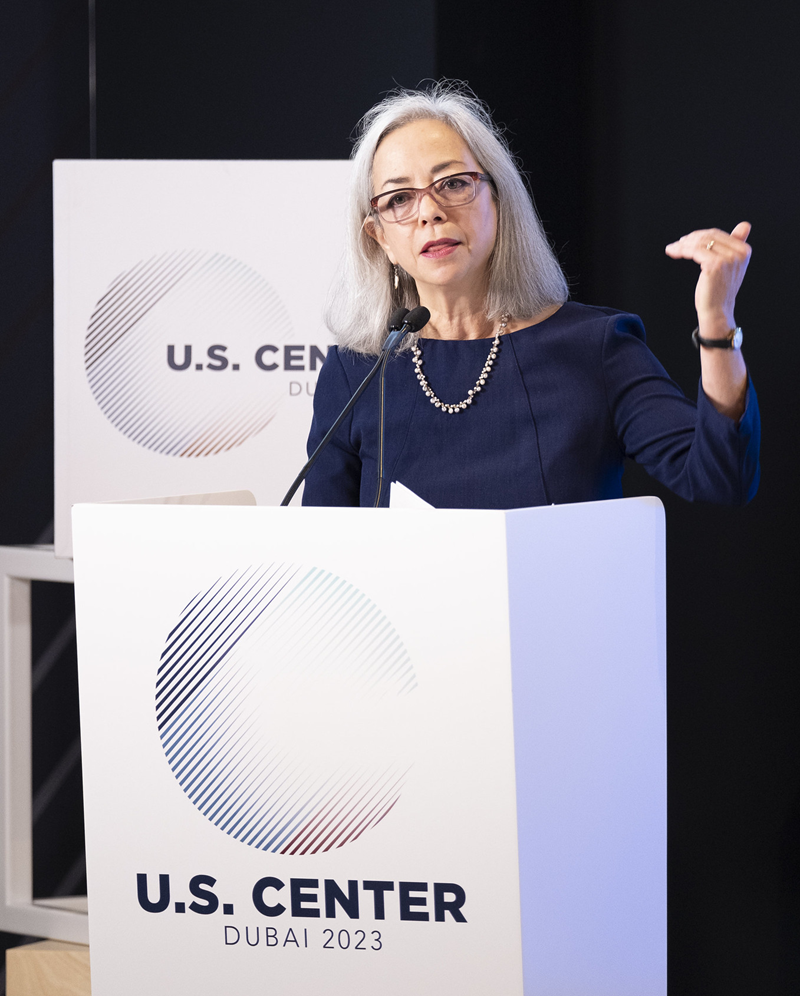 Thea Lee speaks at a podium labeled "U.S. Center, Dubai 2023."