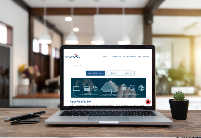   A laptop is open to a webpage reading NASWA Open UI Initiative.