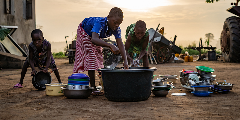 Two girls and their brother wash dishes outside their home in Lome, Togo.