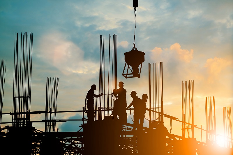 Workers on a job site with sunset behind them. 